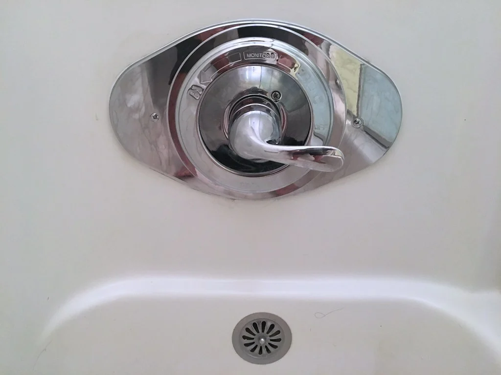 浴室牆上的冷熱水控制閥與浴缸排水孔